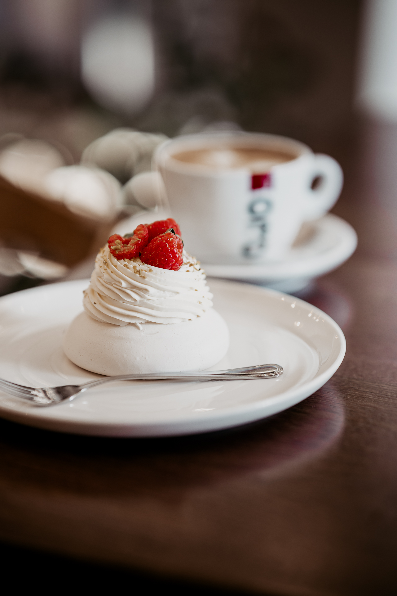 Pavlova tortička, v pozadí šálka s espressom