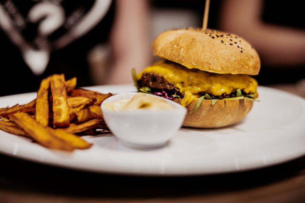 detailný záber na hamburger s batatovými hranolkami a dressingom