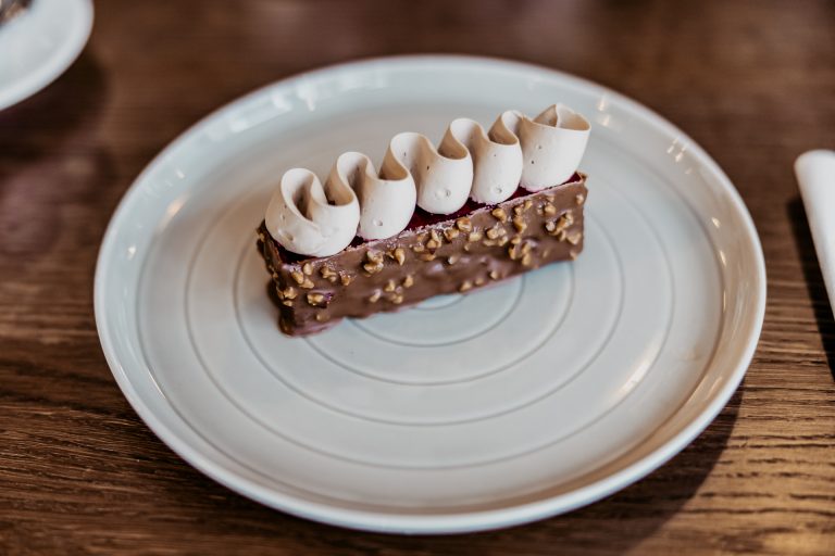 francúzsky čokoládovo-malinový dezert s výraznými orieškami na povrchu, na porcelánovom tanieri